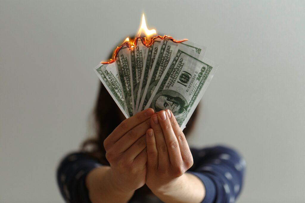 woman holding burning hundred dollar bills representing med spa marketing mistakes that waste budget
